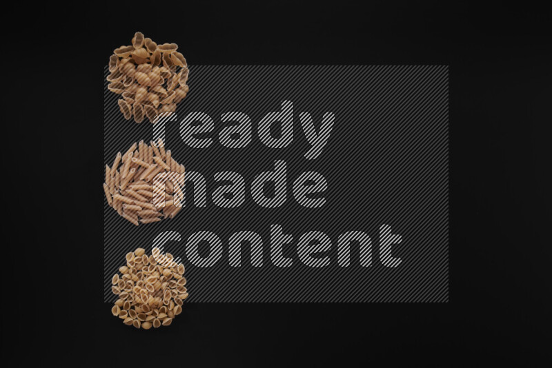 Different pasta types in 3 bunches on black background
