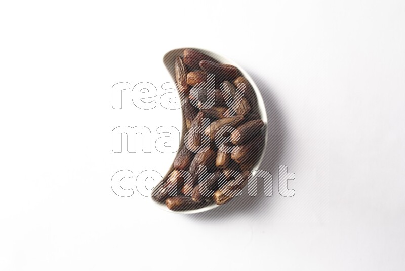 تمر في صحن فخار هلالي على خلفية بيضاء