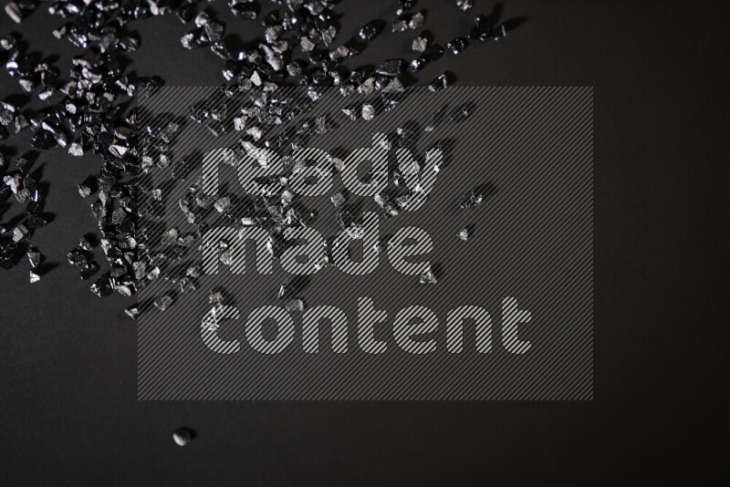 Black shimmering fragments of glass scattered on a black background