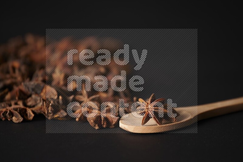 Star Anise in a wooden spoon and spreading on a black flooring