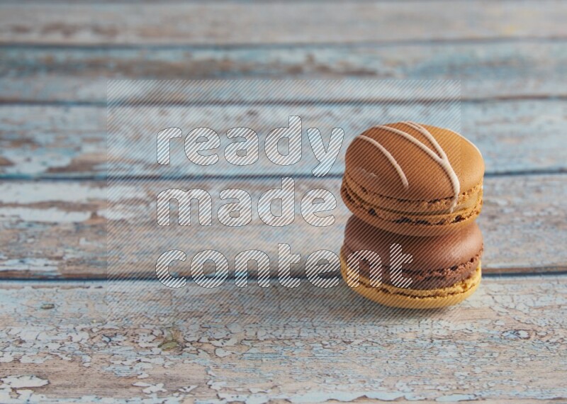 45º Shot of of two assorted Brown Irish Cream, and Yellow, and Brown Chai Latte macarons  on light blue background