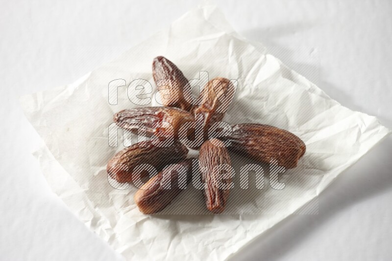 Dried dates on a crumpled piece of paper on a white background in different angles