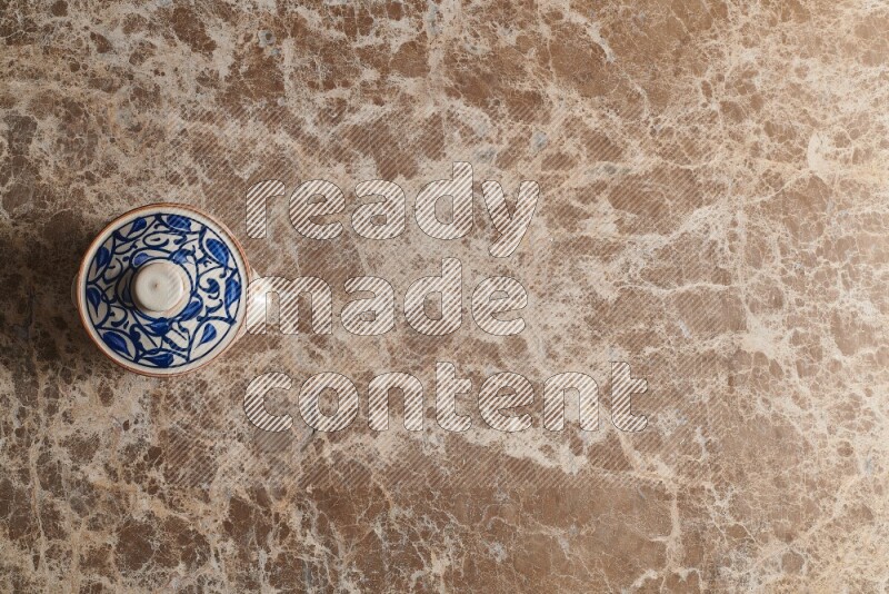 A multicolored pottery pot on beige marble background