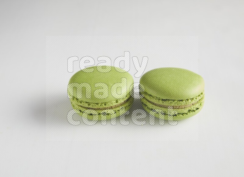 45º Shot of two Green Pistachio macarons on white background