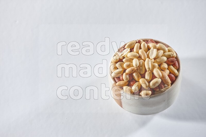 A beige ceramic bowl full of peeled peanuts on a white background in different angles