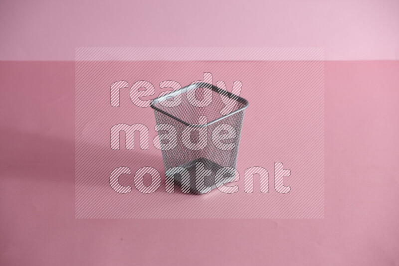 Pens, pencils and other different school supplies in a metal pen holder on rose background