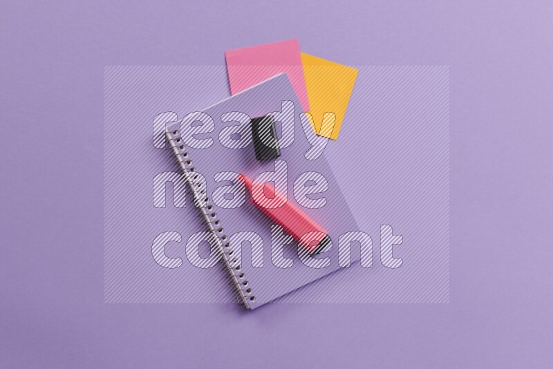 A purple notebook with different school supplies on purple background