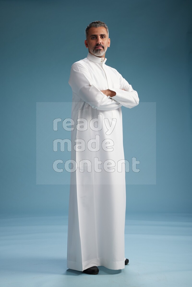 Saudi man waring thob posing to the camera on blue background