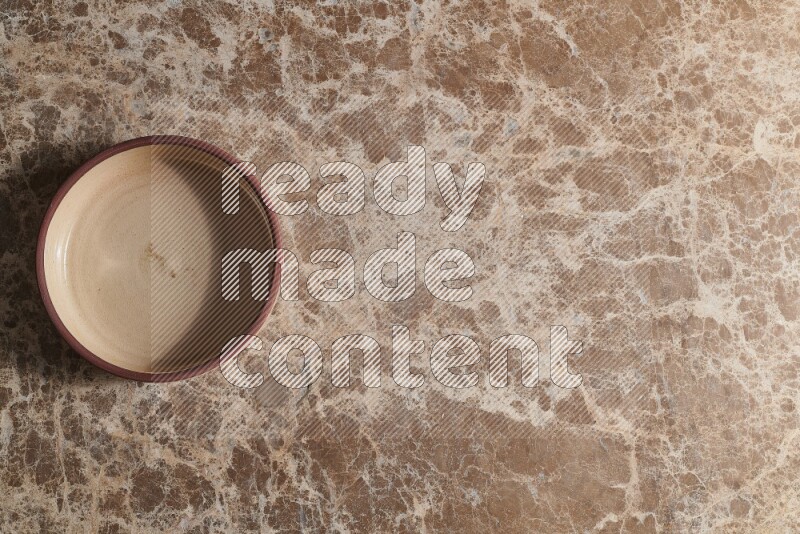 A beige pottery oven plate on beige marble background