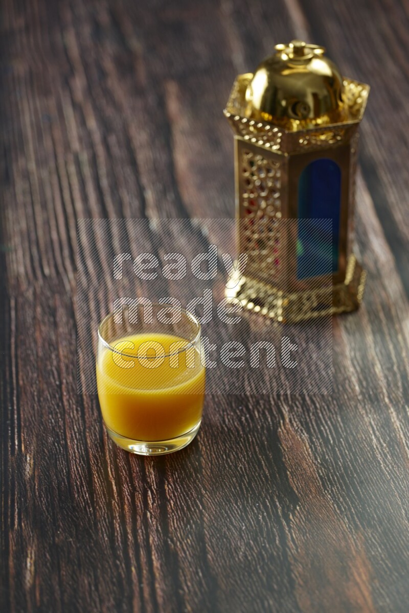 A golden lantern with different drinks, dates, nuts, prayer beads and quran on brown wooden background