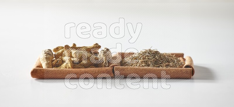 2 squares of cinnamon sticks full of cumin and turmeric fingers on white flooring