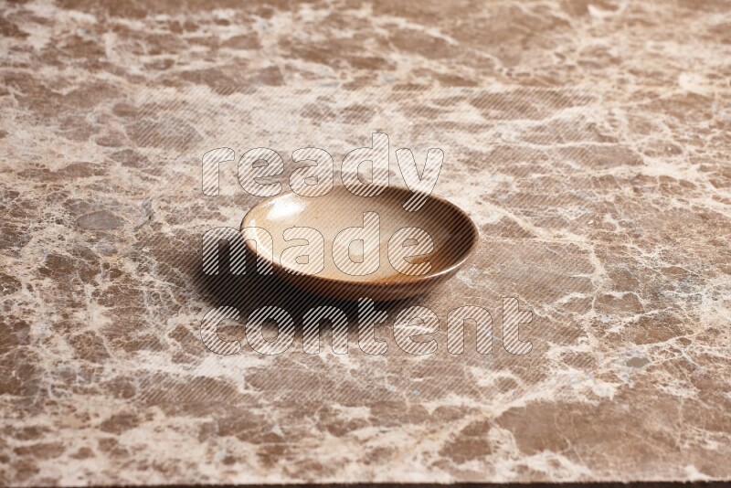 A beige pottery plate on beige marble background