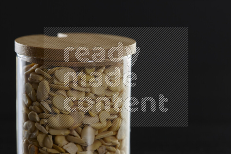 Crushed beans in a glass jar on black background