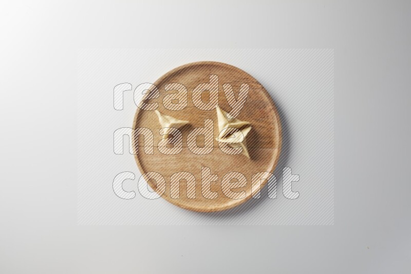 Three Sambosas on a wooden round plate on a white background