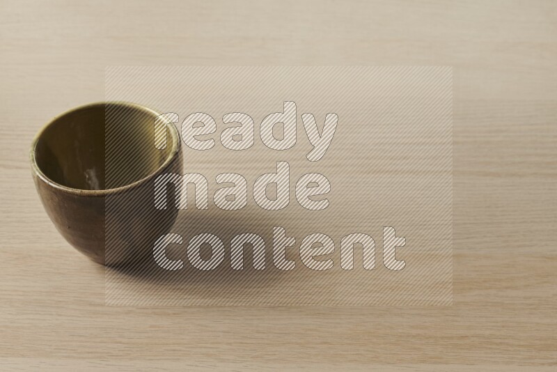 A multicolored pottery cup on light wooden background