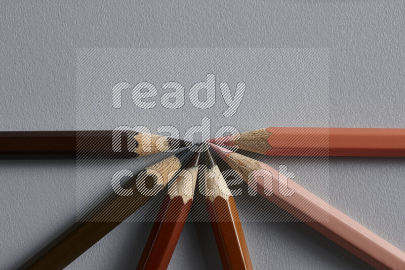 An arrangement of colored pencils in different colors on grey background
