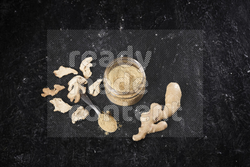 A glass jar full of ground ginger powder on black background