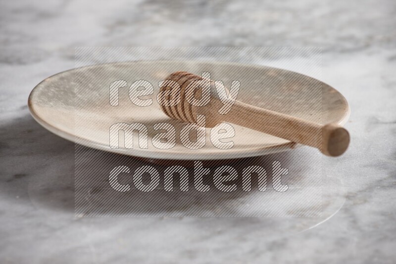 Multicolored pottery plate with wooden honey dipper in it on grey marble background