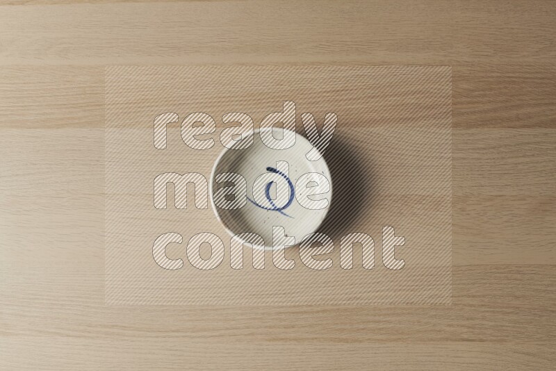 A multicolored pottery bowl on light wooden background