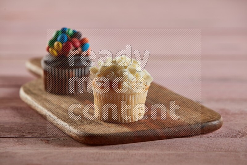 Vanilla mini cupcake topped with white chocolate curls on a wooden board