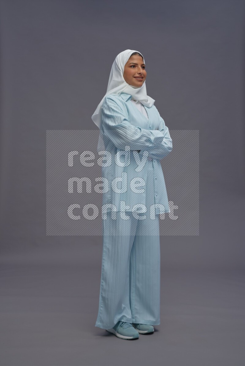 Saudi woman wearing hijab clothes standing with crossed arms on gray background