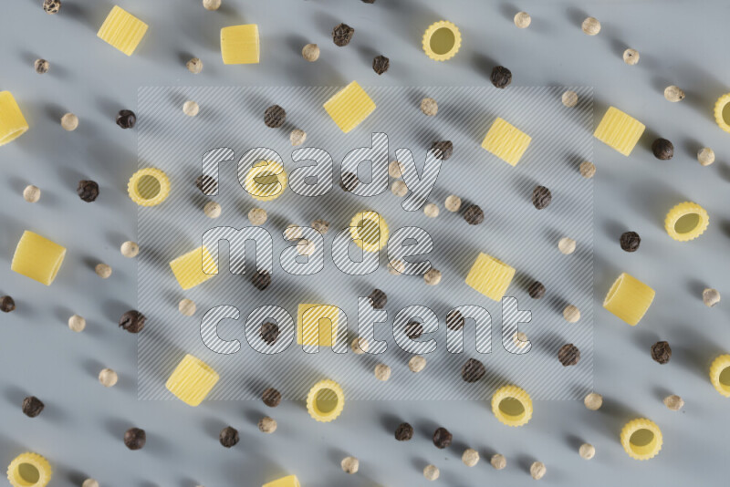 Raw pasta with different ingredients such as cherry tomatoes, garlic, onions, red chilis, black pepper, white pepper, bay laurel leaves, rosemary, cardamom and mushrooms on light blue background