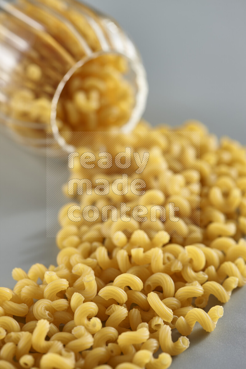 Flipped jar full of raw pasta on light blue background