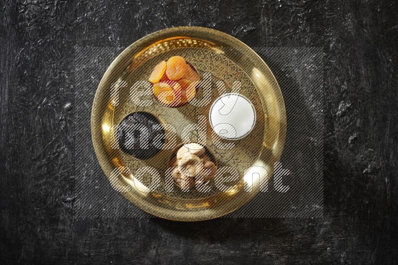Dried fruits in metal bowls with sobya on a tray in dark setup