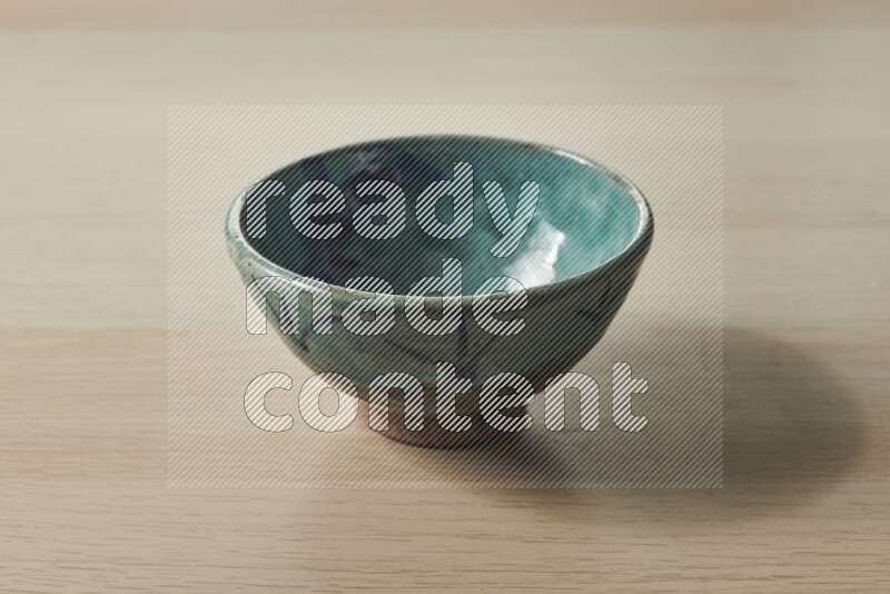 A decorative pottery bowl on light wooden background