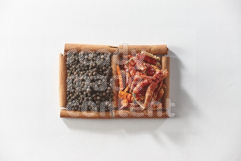 2 squares of cinnamon sticks full of red dried chilis and black pepper on white flooring