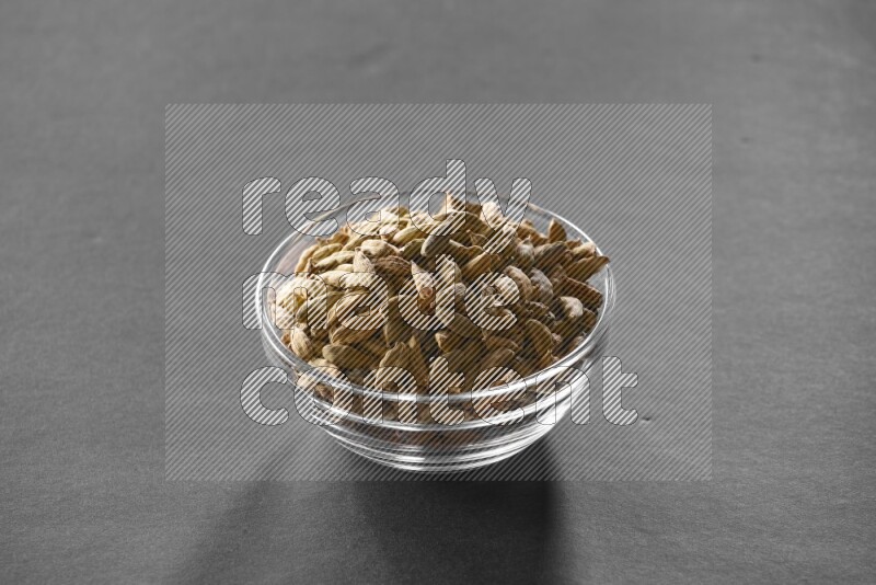 A glass bowl full of cardamom on black flooring