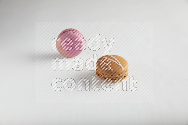 45º Shot of of two assorted Brown Irish Cream, and Purple Strawberry macarons on white background