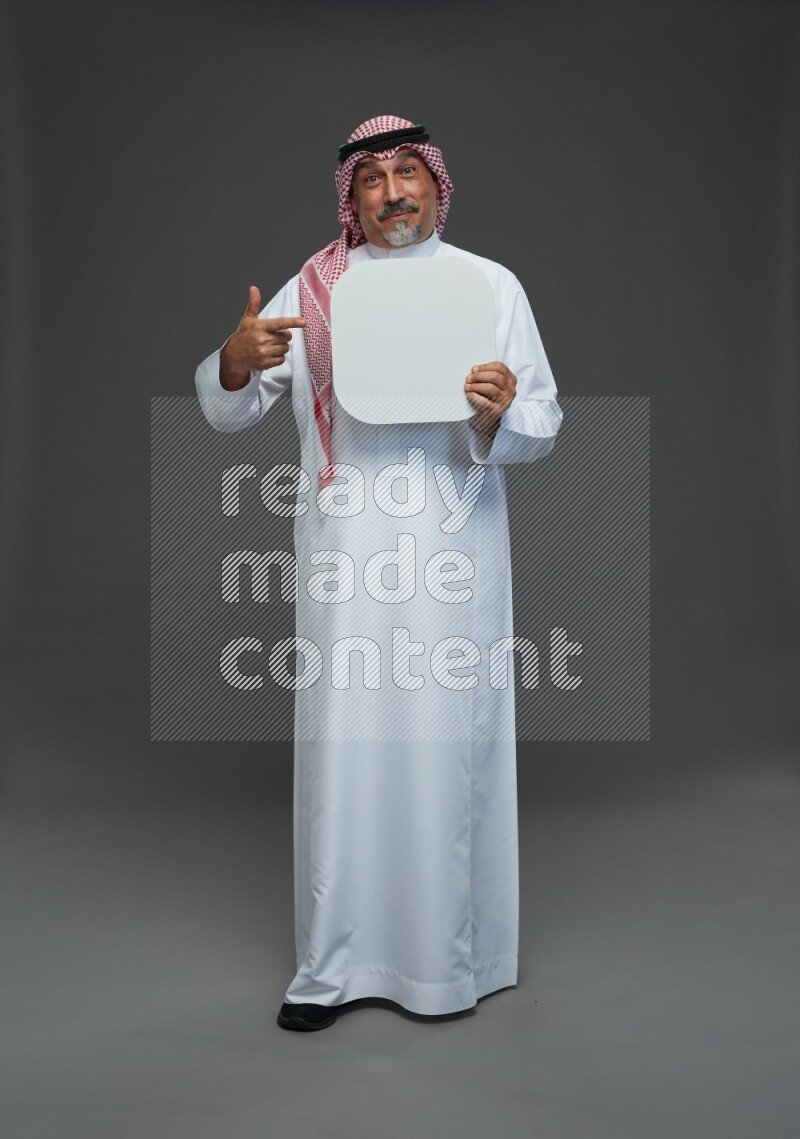 Saudi man with shomag Standing holding social media sing on gray background