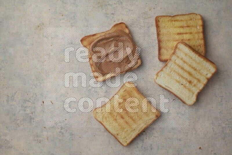Creamy peanut butter on a toasted white toast and toasted white toast slices on a light blue textured background