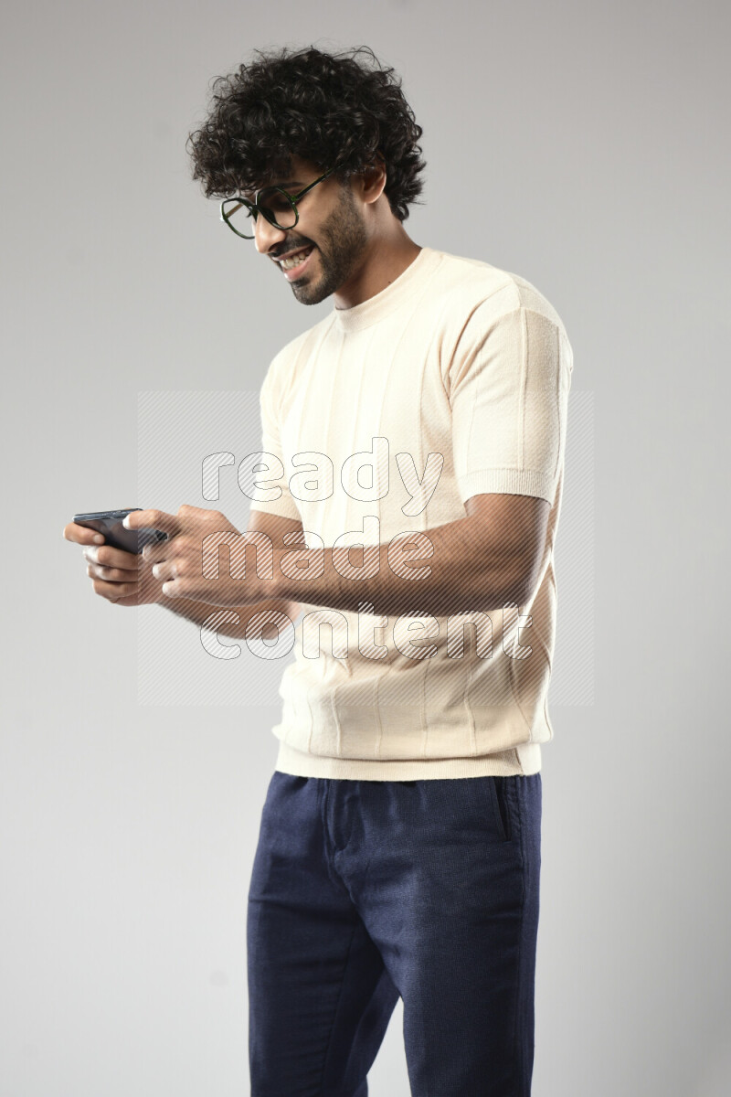 A man wearing casual standing and gaming on the phone on white background