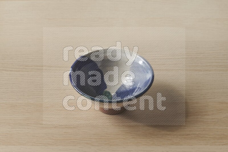 A multicolored pottery bowl on light wooden background