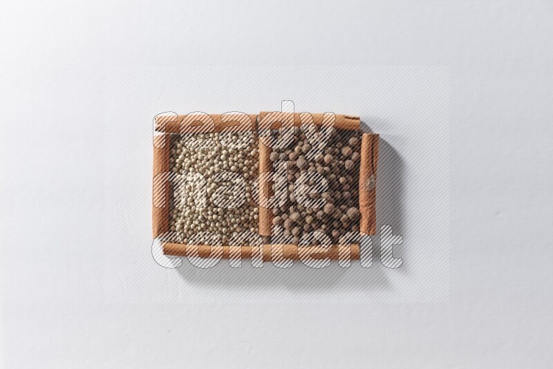 2 squares of cinnamon sticks full of white pepper and allspice on white flooring