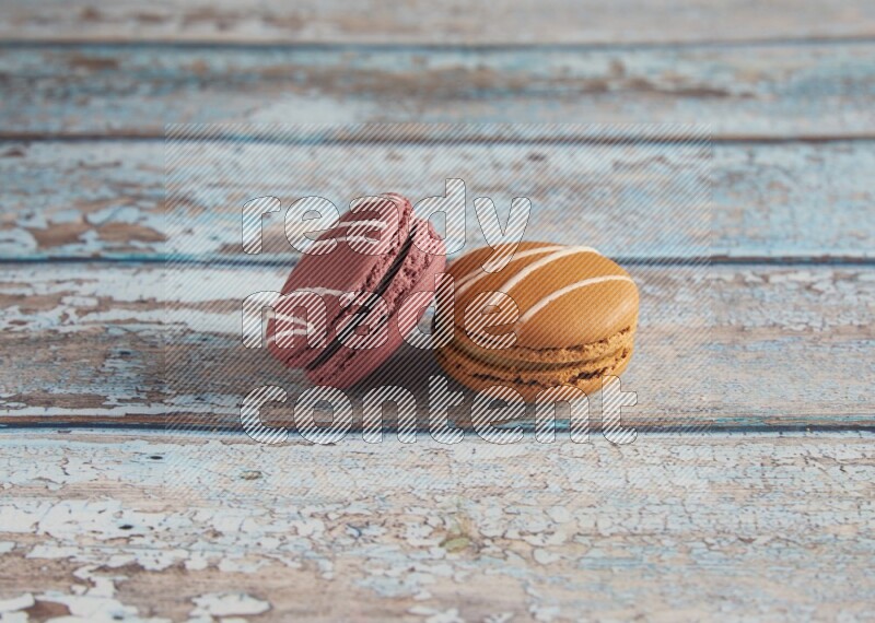 45º Shot of of two assorted Brown Irish Cream, and Red Poppy Flower macarons  on light blue background