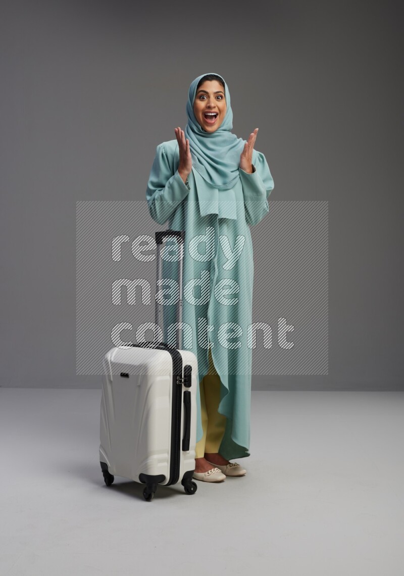 Saudi Woman wearing Abaya standing holding Travel bag on Gray background