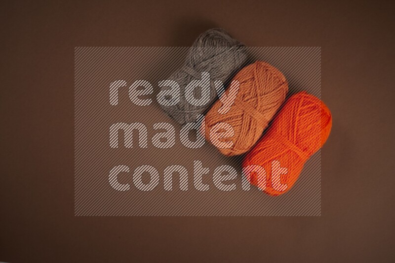 An orange collection of sewing and tailoring tools arranged on a brown background