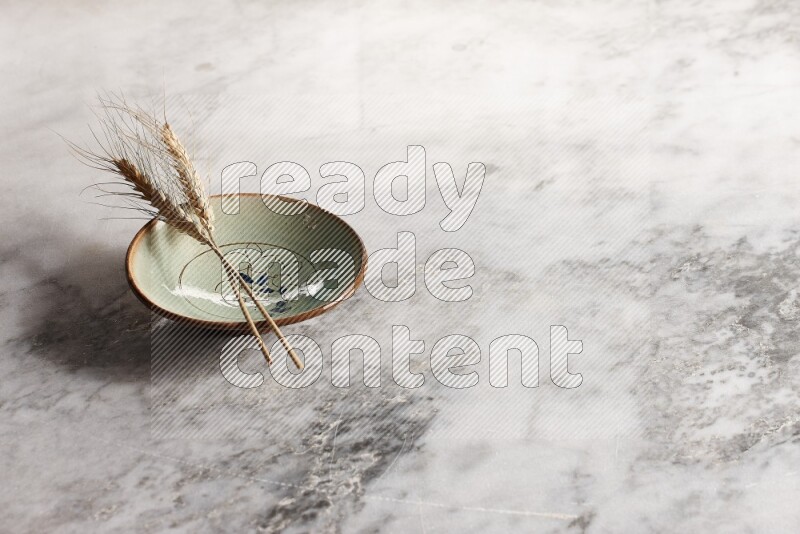 Wheat stalks on decorative pottery plate on grey marble background