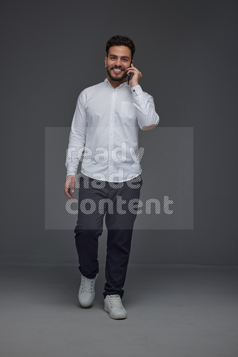 A man wearing smart casual talking in the phone eye level on a gray background