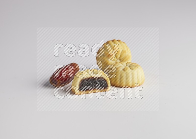 Three Pieces of Maamoul filled with date one of them is cut direct on white background