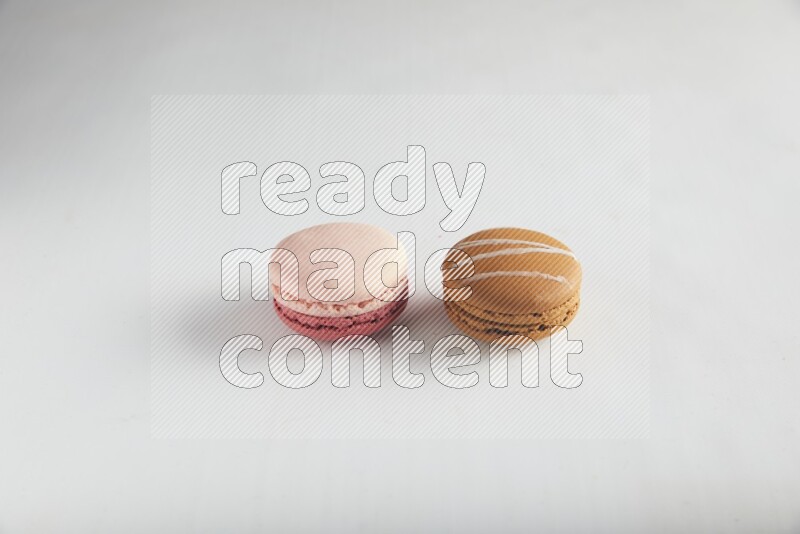 45º Shot of of two assorted Brown Irish Cream, and Pink Litchi Raspberry macarons on white background