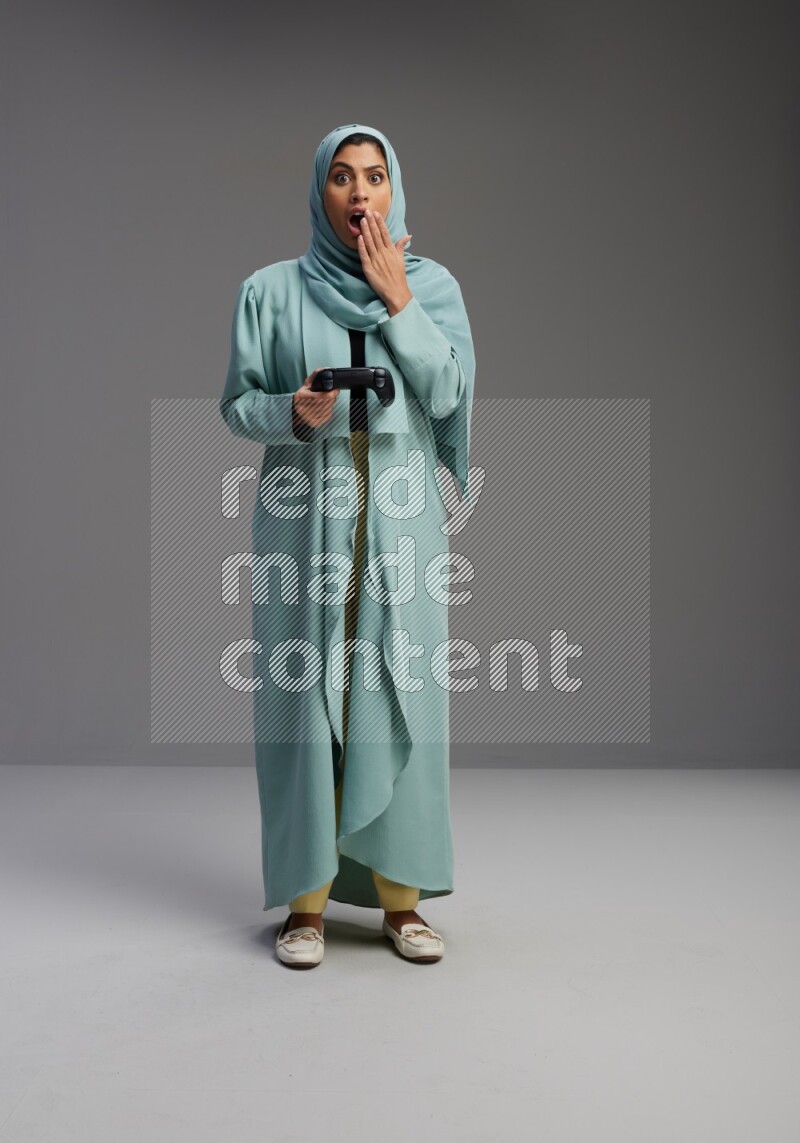 Saudi Woman wearing Abaya standing Playing Games on Gray background