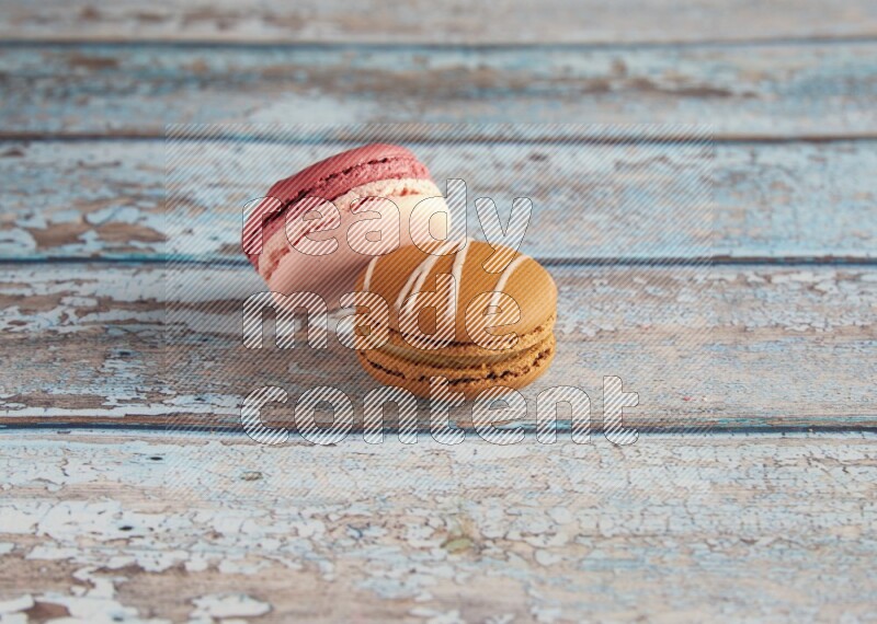 45º Shot of of two assorted Brown Irish Cream, and Pink Litchi Raspberry macarons on light blue background