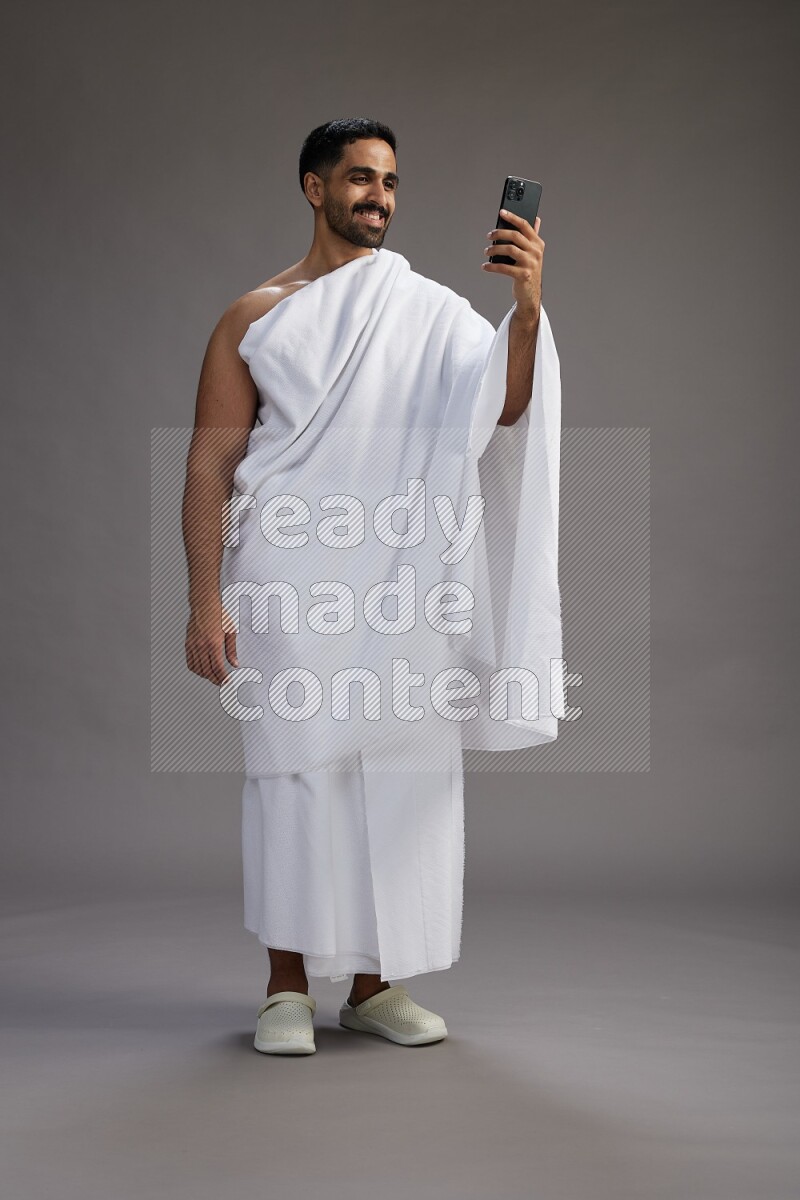 A man wearing Ehram Standing taking selfie on gray background