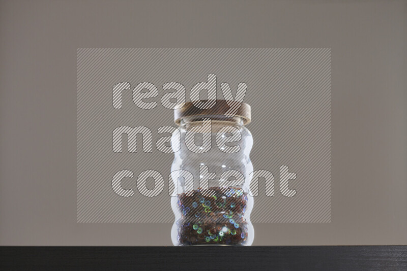 Sequins in a glass jar on black background