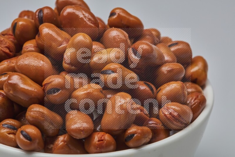 Close up shot of cooked fava beans (foul) in a container on white background