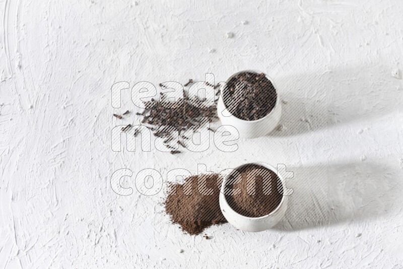 وعاءين من السيراميك بيج اللون، أحدهما مملوء بالقرنفل والآخر مملوء بالبودرة على أرضية بيضاء